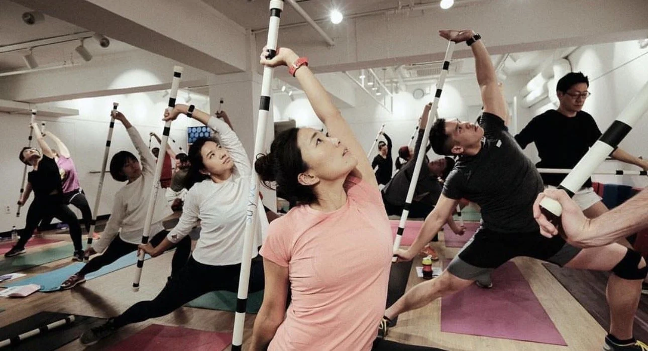 Powersweat with coach Dean Myers leading a fitness class with many people stretching and exercising in Seoul at lululemon.