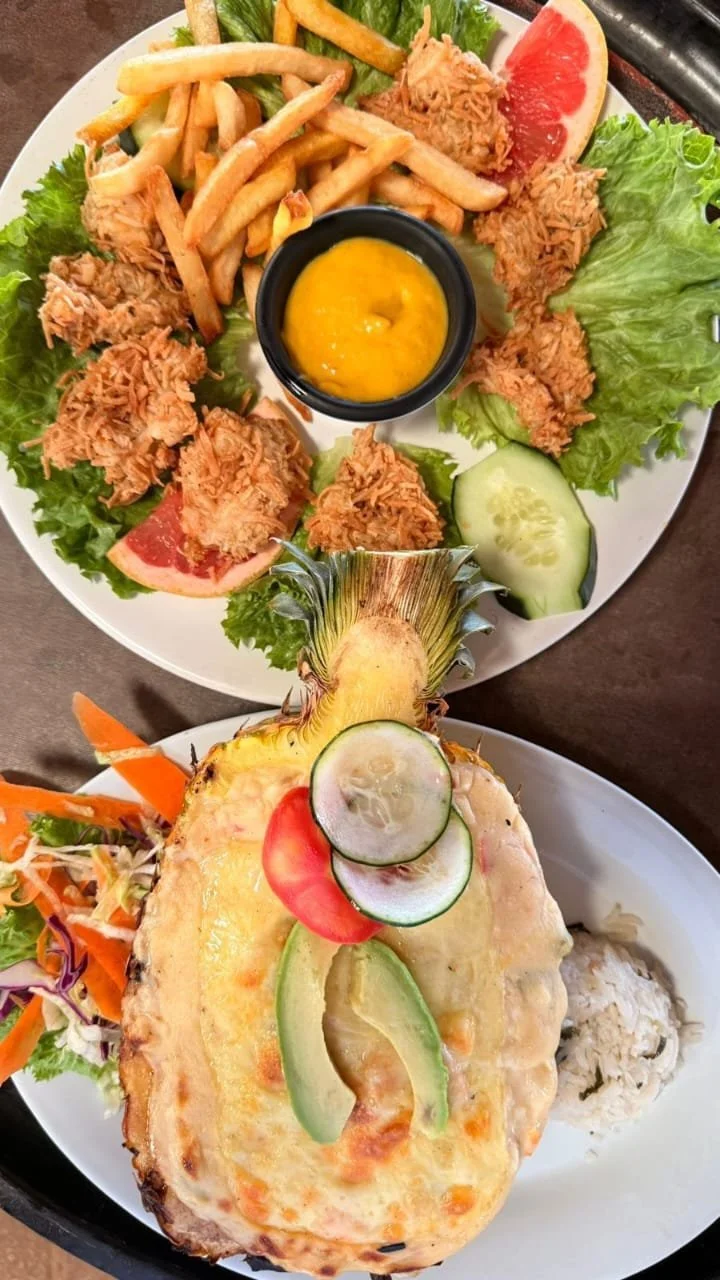 Plato con pollo empanizado, ensalada con verduras frescas, y una porción de pasta, acompañado de papas fritas y salsa de mostaza con miel en un plato y otra comida con fruta y ensalada