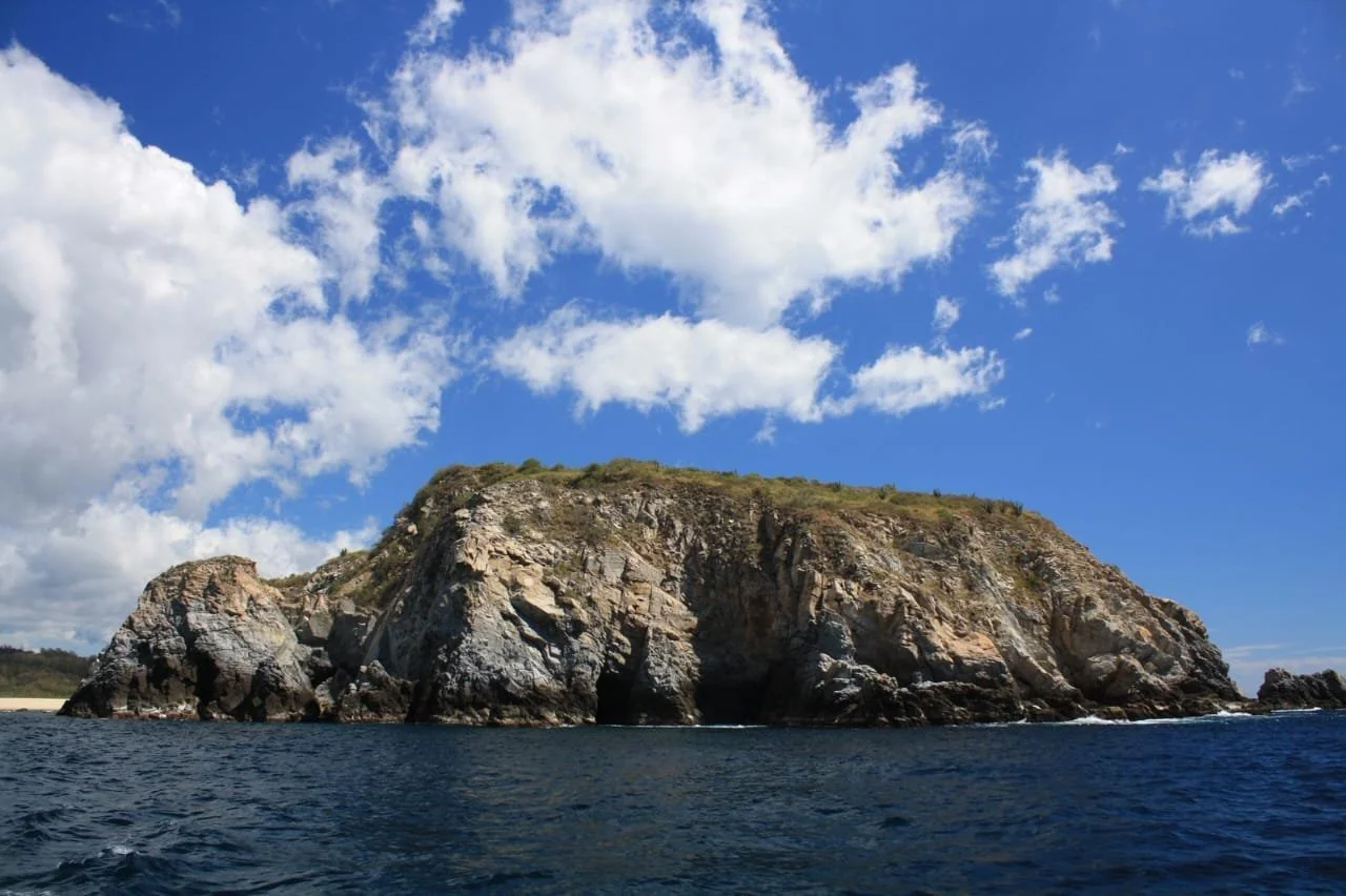 Isla rocosa en el mar con cielo despejado y algunas nubes.
