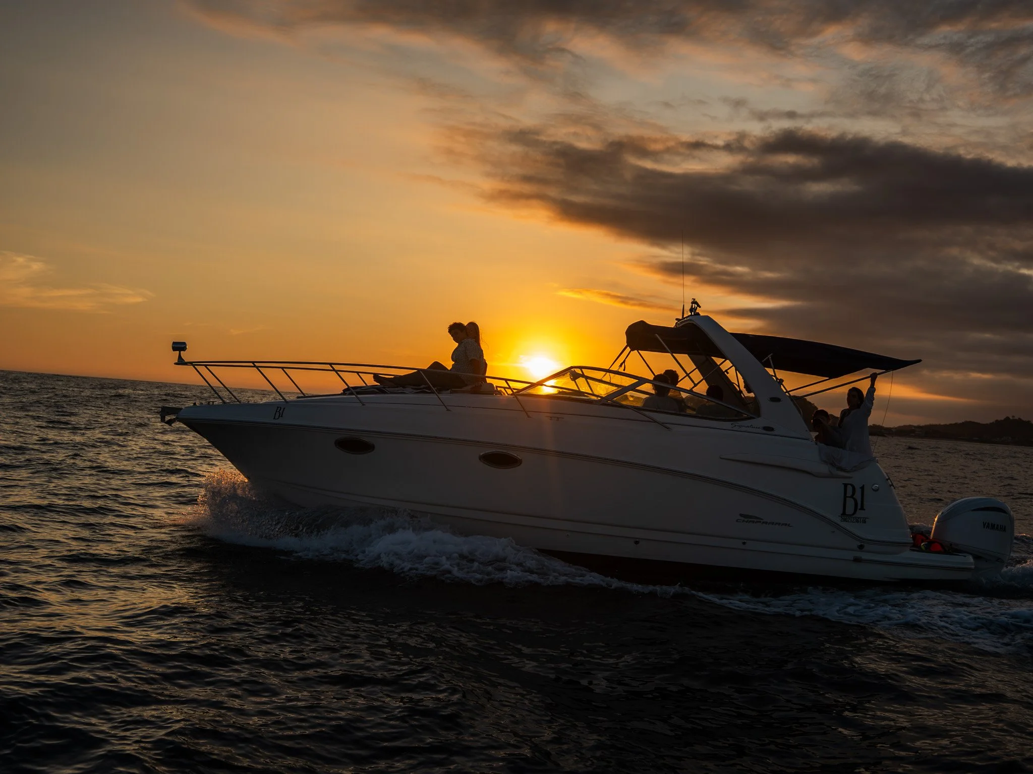 Un yate navegando en el mar durante el atardecer con un cielo con nubes y colores cálidos