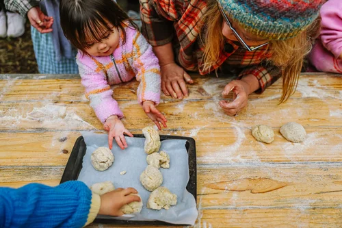 Two children kneading dough together on a floured tray