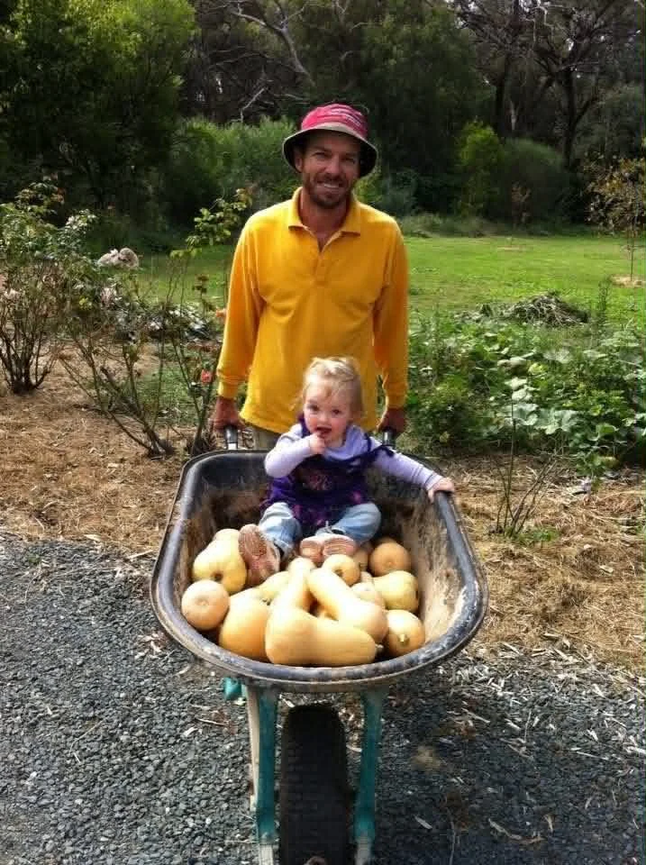 Jase pushing a wheelbarrow with a child inside