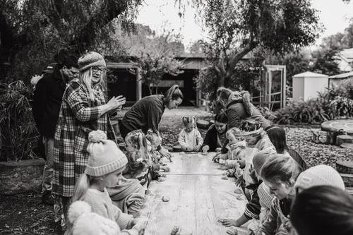 Black and white photo of a group sitting outdoors during story time