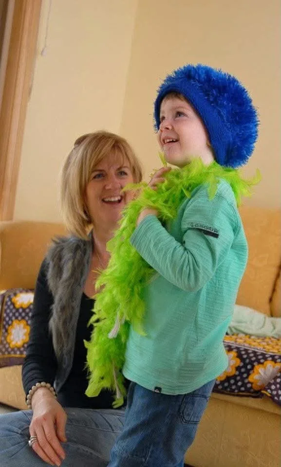 Child in a green feather boa and blue hat