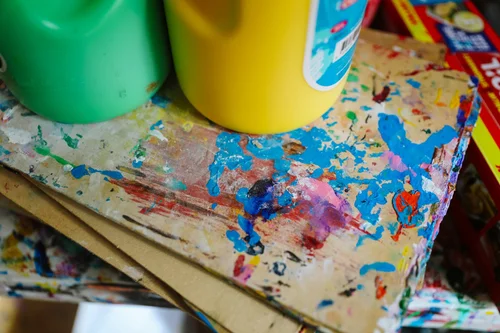 Colourful paint bottles and tins of paintbrushes ready for craft time