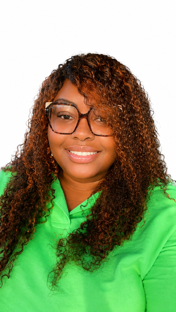 A woman with curly hair wearing glasses and a bright green top, smiling against a white background.