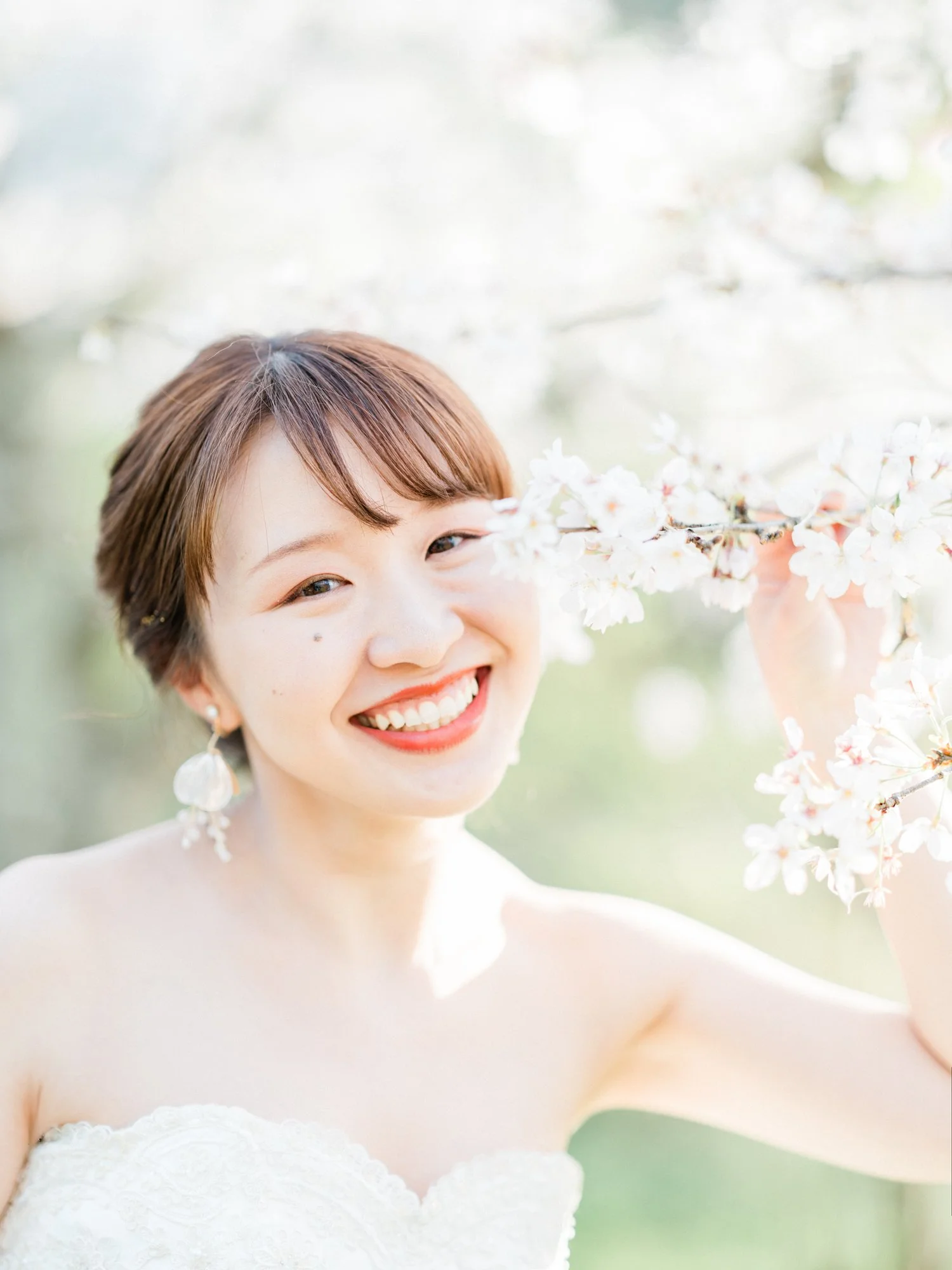 笑顔の女性が桜の花を持っている写真。