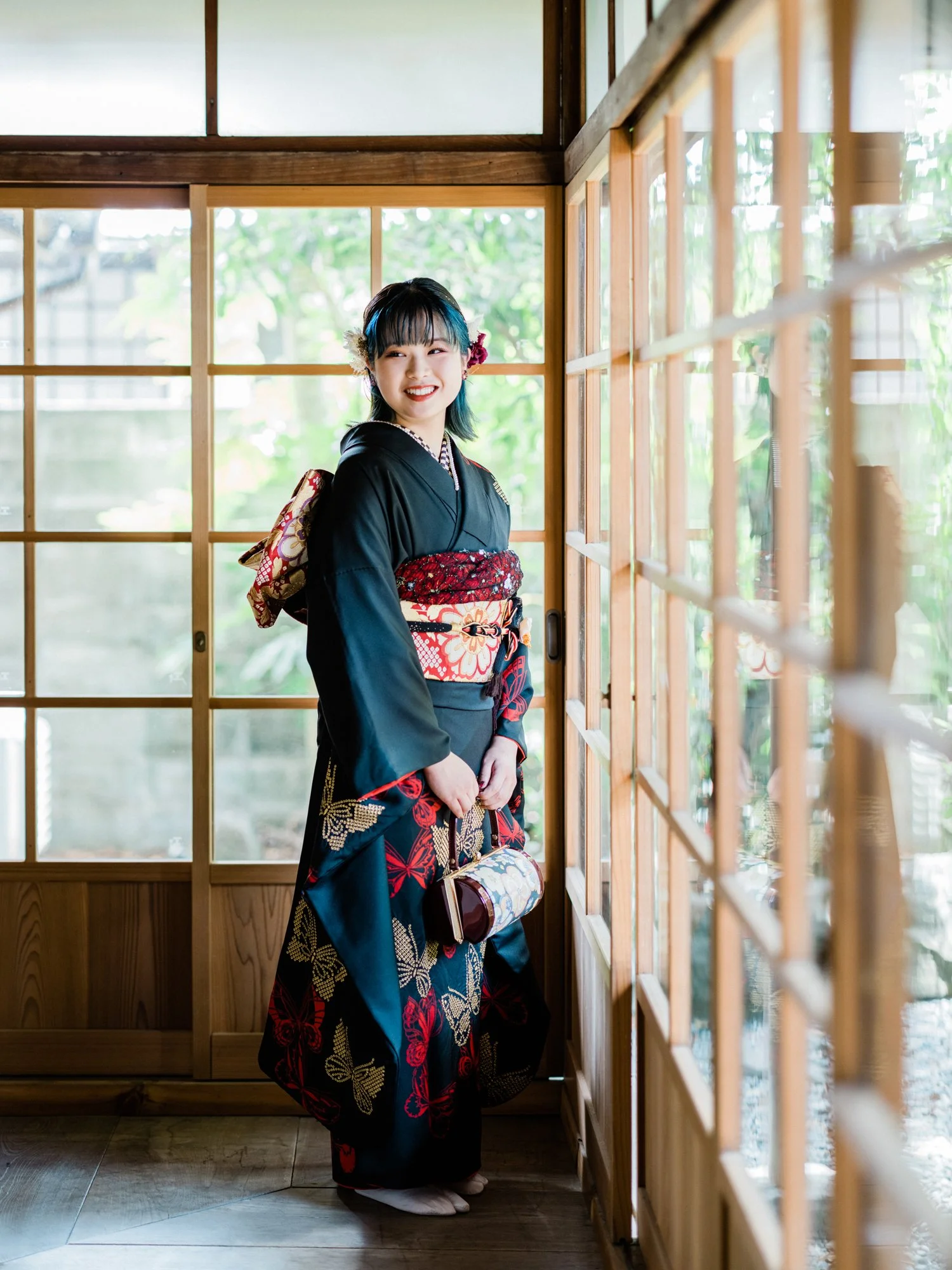 振袖を着た成人の女性が伝統的な古民家の中で笑顔でいる様子。