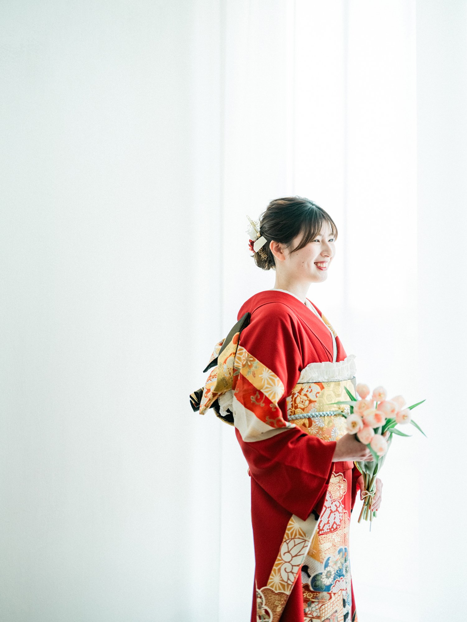花束を持ち、笑顔の女性が伝統的な振袖、成人の前撮り写真。