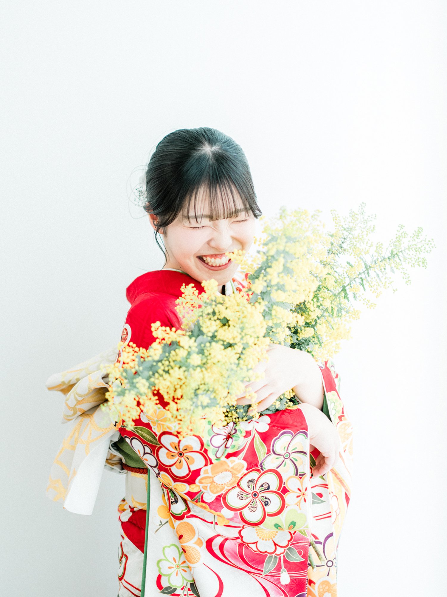 笑顔で花を持つ女性が振袖を着ている写真