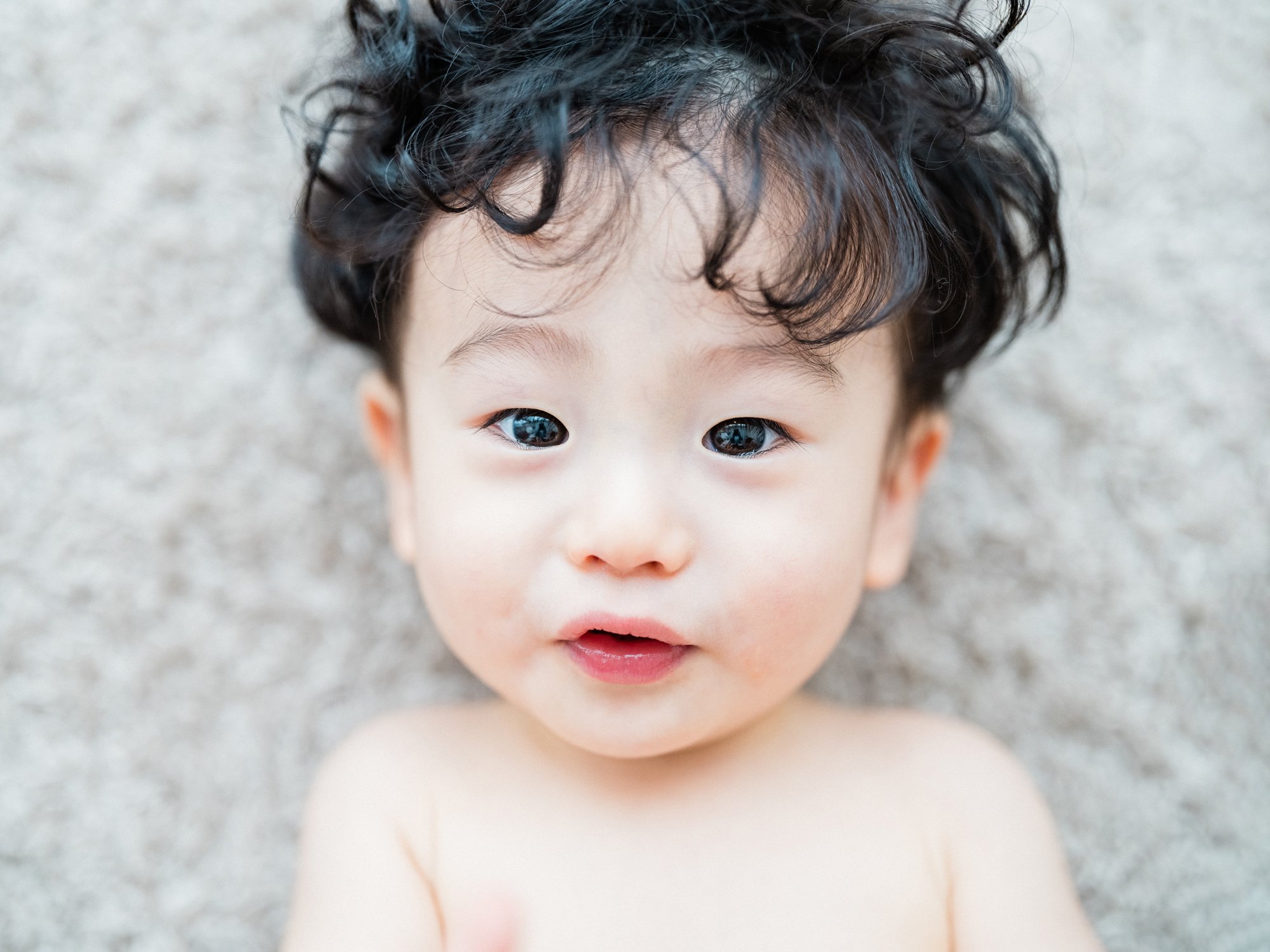 子供の顔のアップ。黒い巻き毛と大きな瞳が印象的。