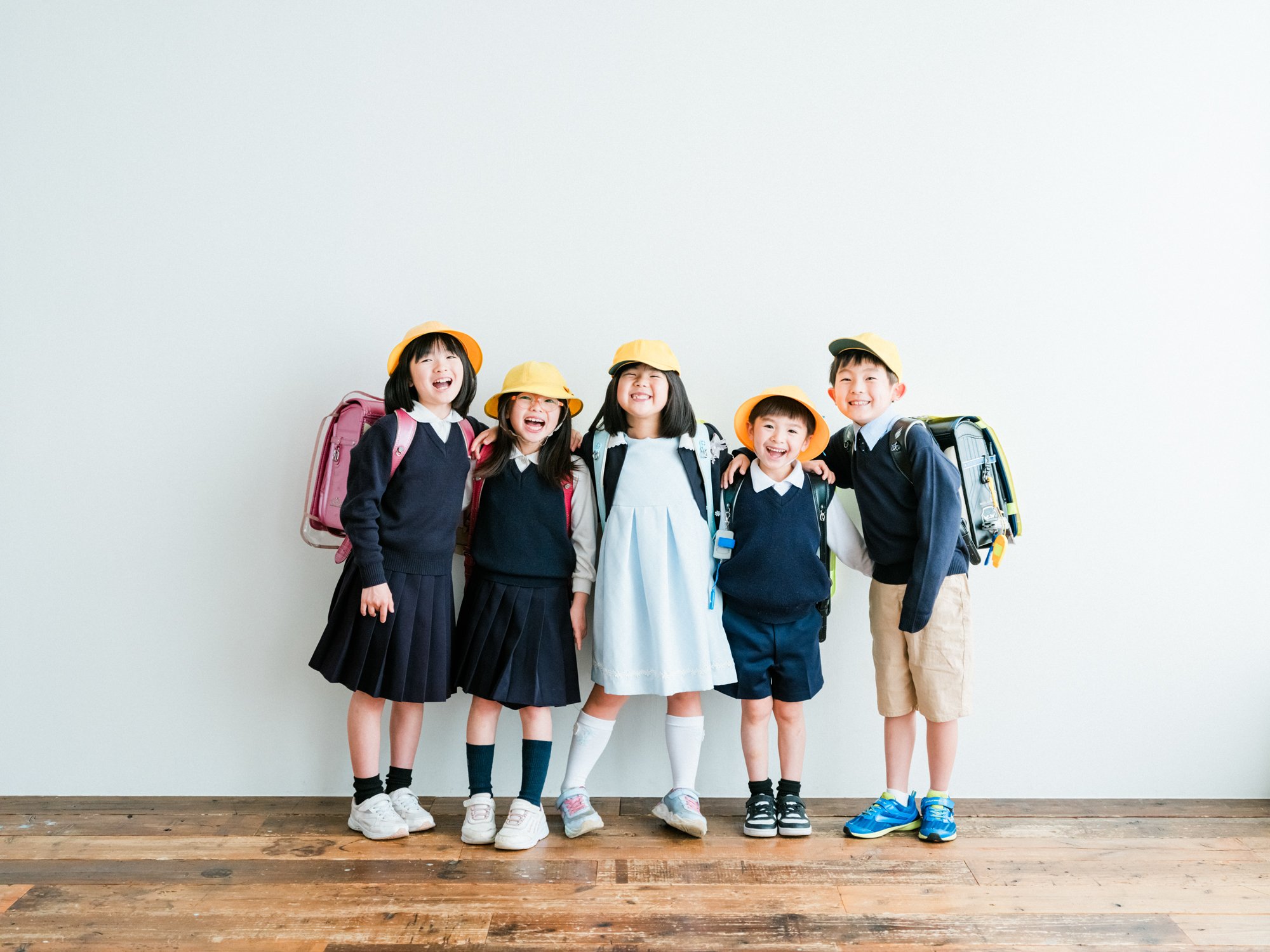 笑顔の小学生の子供たちが並んでいて、黄色い帽子をかぶっている。