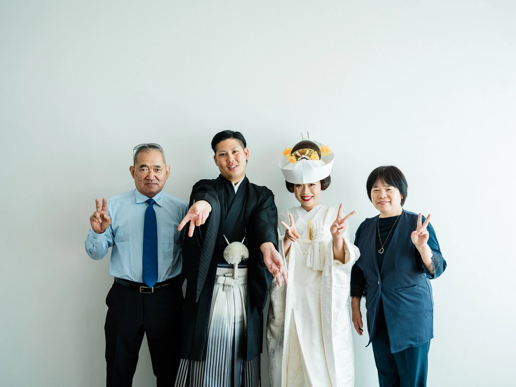 伝統的な和装を着た新郎新婦、ポーズをとりながら笑顔を見せているグループ写真です。