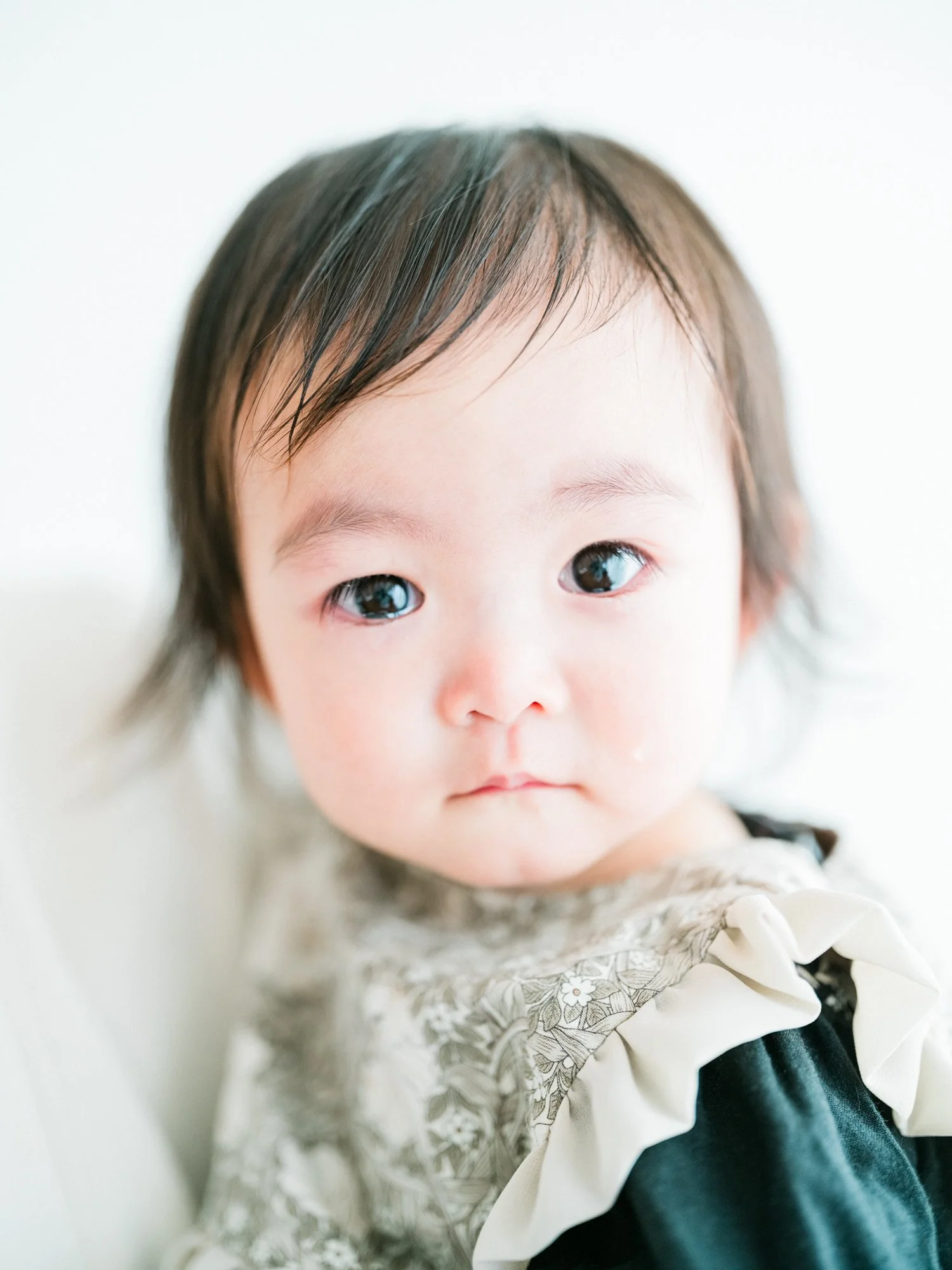 白い背景に、黒と茶色の髪を持つ幼い子供の顔。目が大きく、少し涙目。