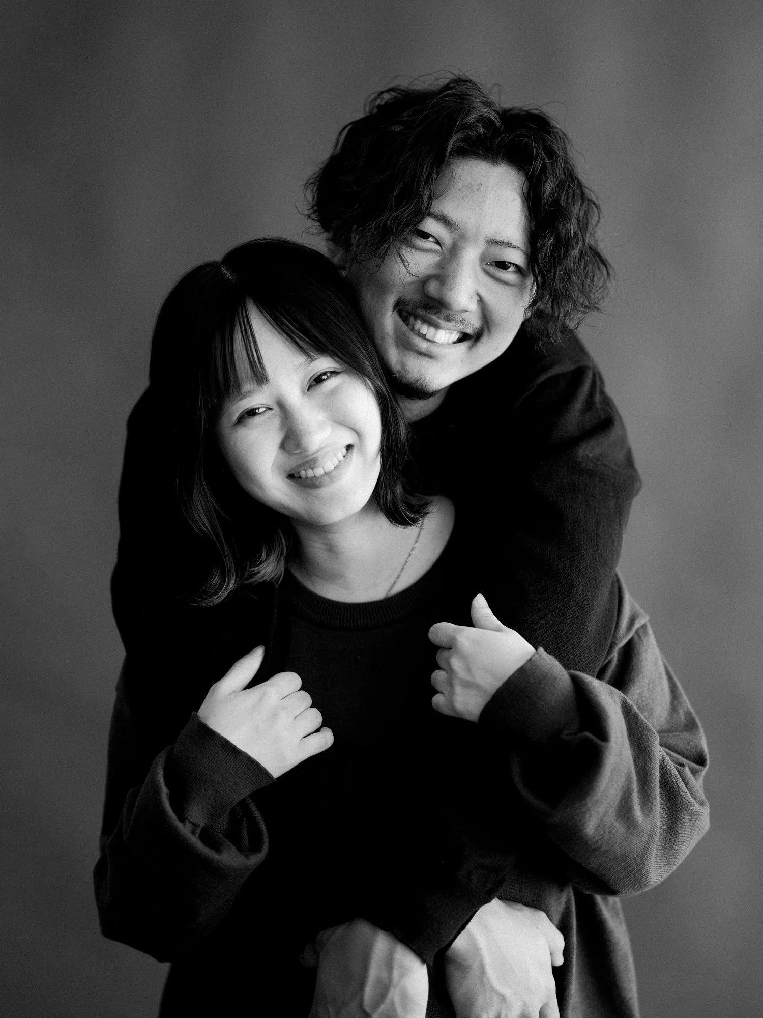 笑顔の若い男性と女性が抱き合っているポートレート写真。