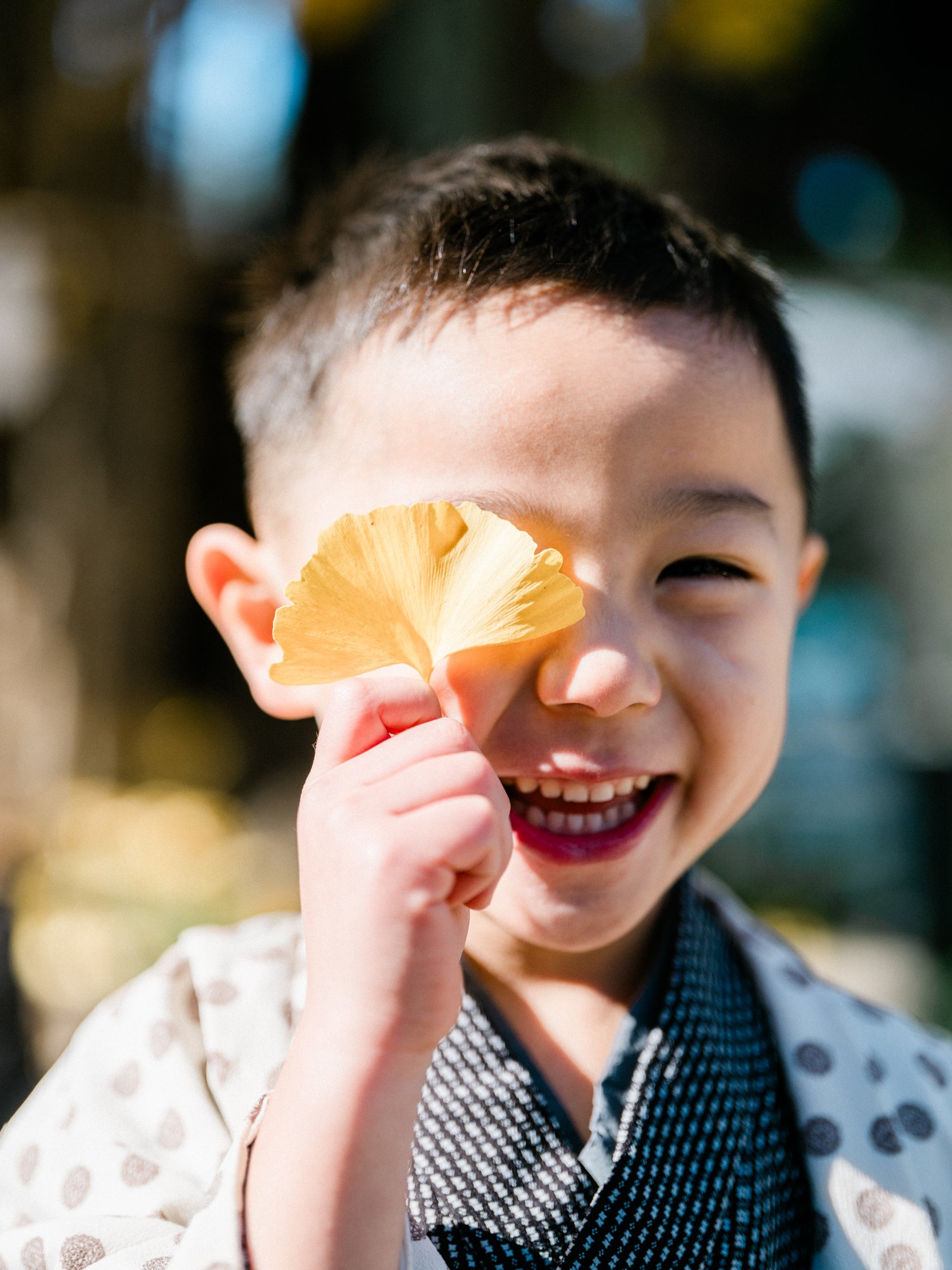 笑顔の子供が黄色い銀杏の葉を持って笑っている。