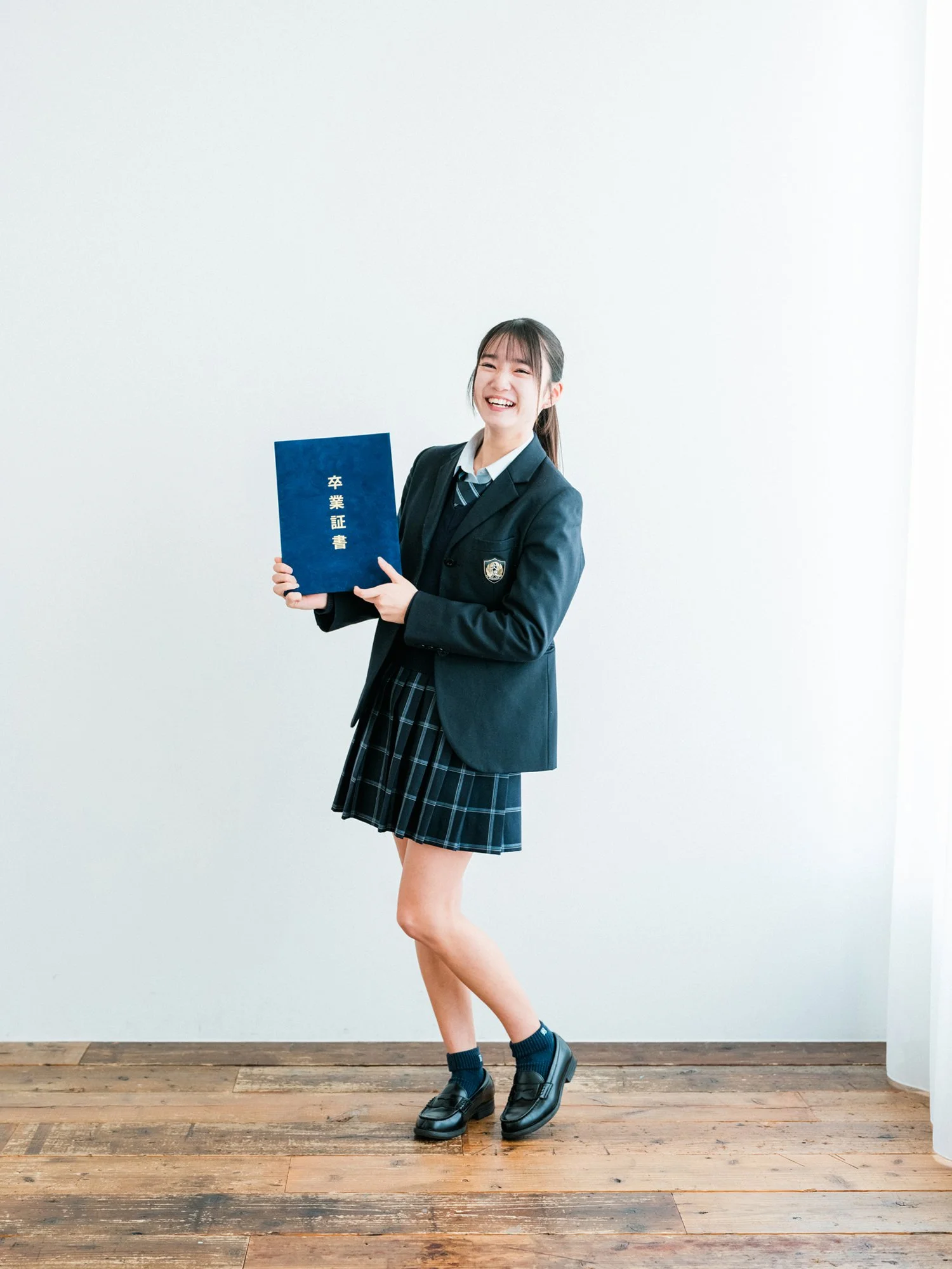 高校制服の女の子が笑顔で卒業証書を持っています。