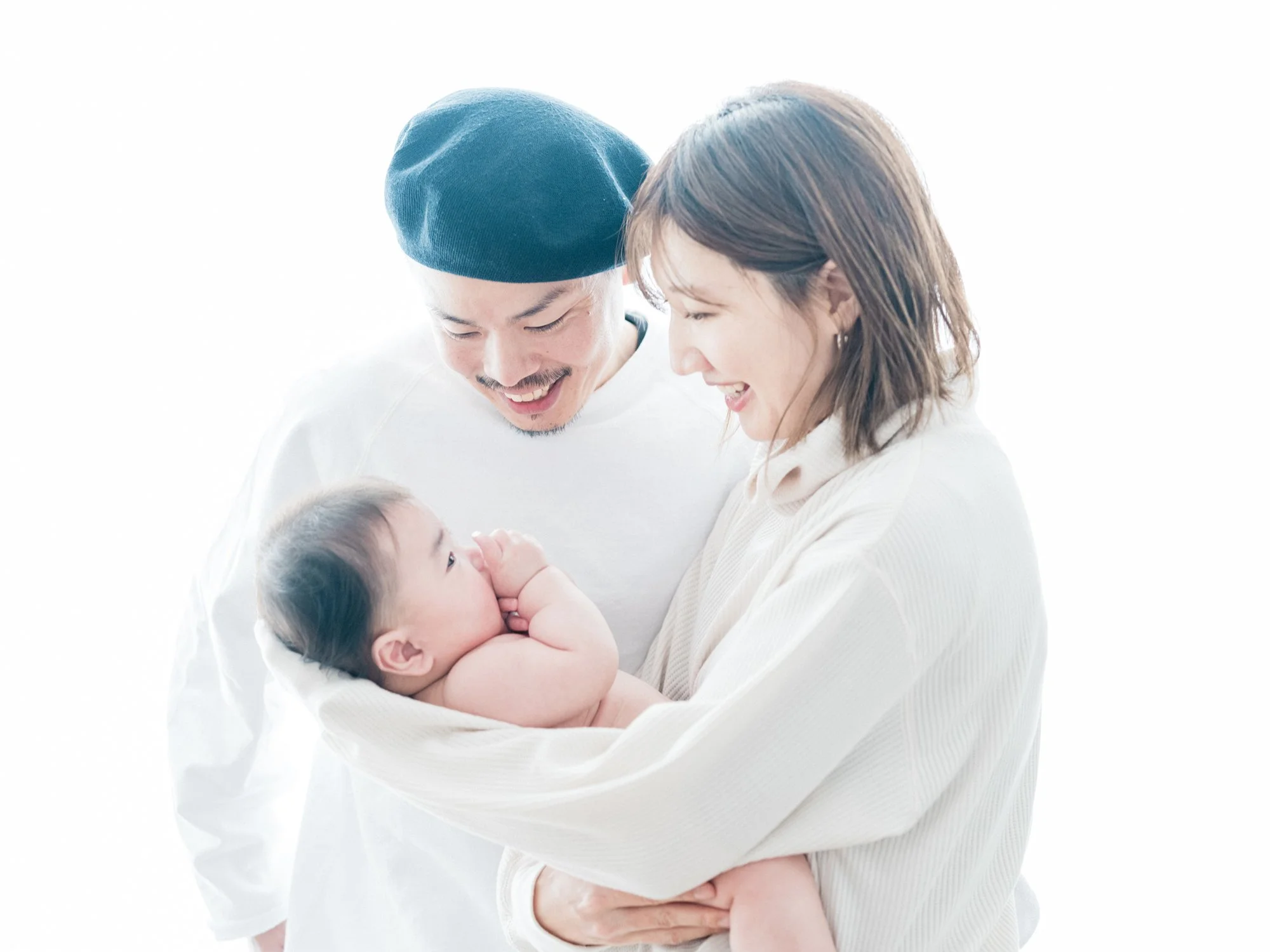 赤ちゃんを抱きしめる家族の姿。父親、母親、幼い子供と笑顔で交流している暖かい家庭の場面。