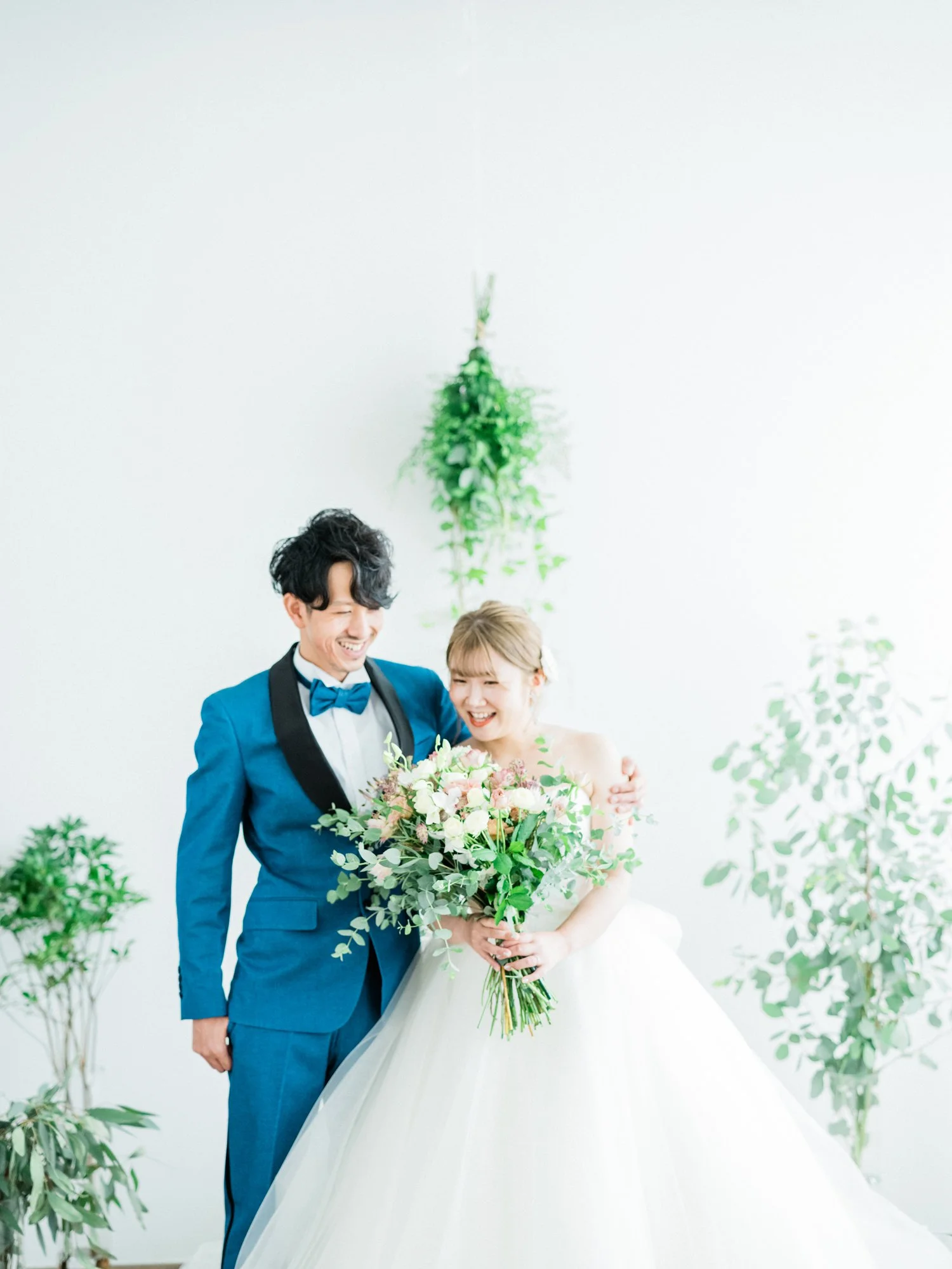 結婚式の新郎新婦が花束を持ち、笑顔で喜び合っている場面。