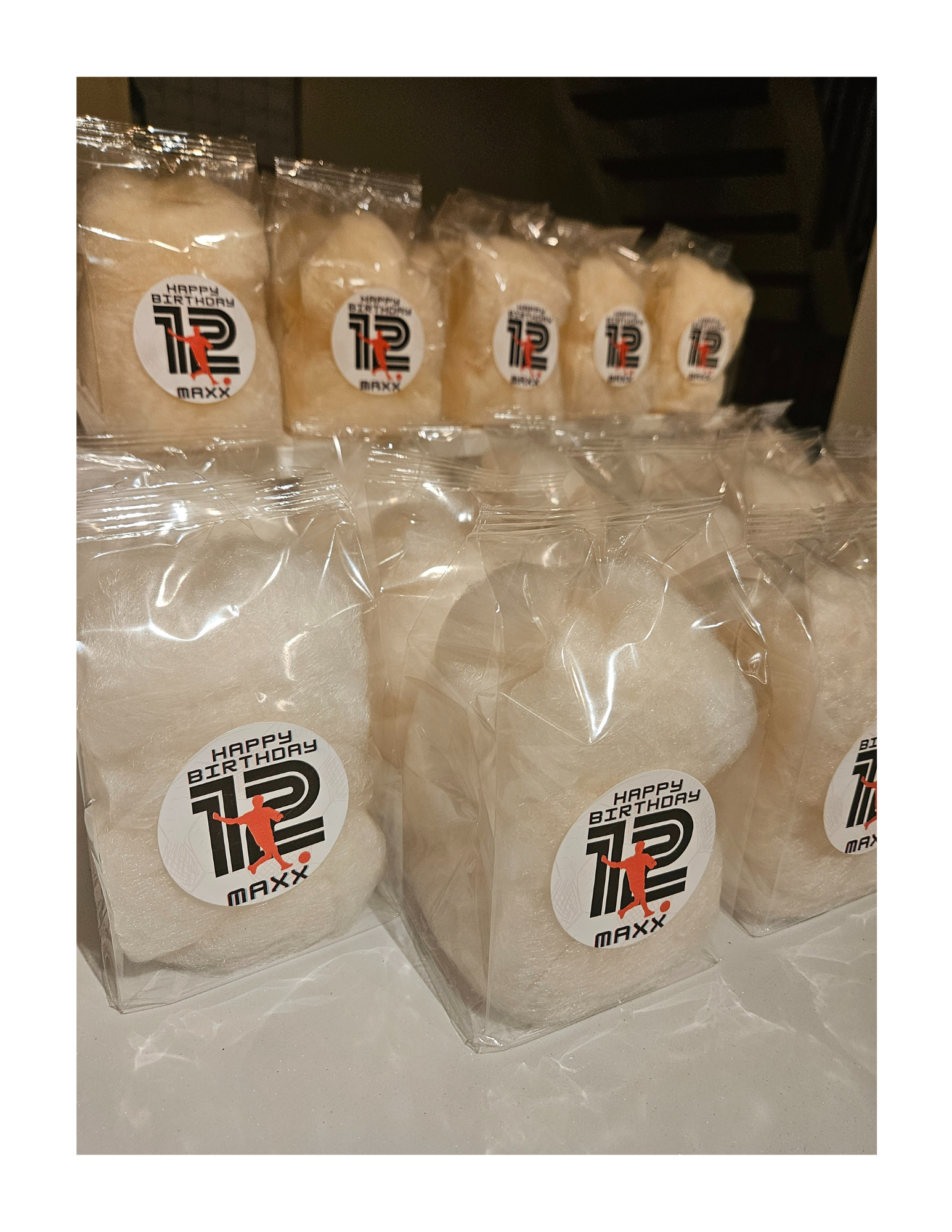 Clear gusseted bag of dye-free cotton candy with a birthday celebration sticker that reads 'Happy Birthday 12 Maxx' and features a silhouette of a person kick a soccer ball.