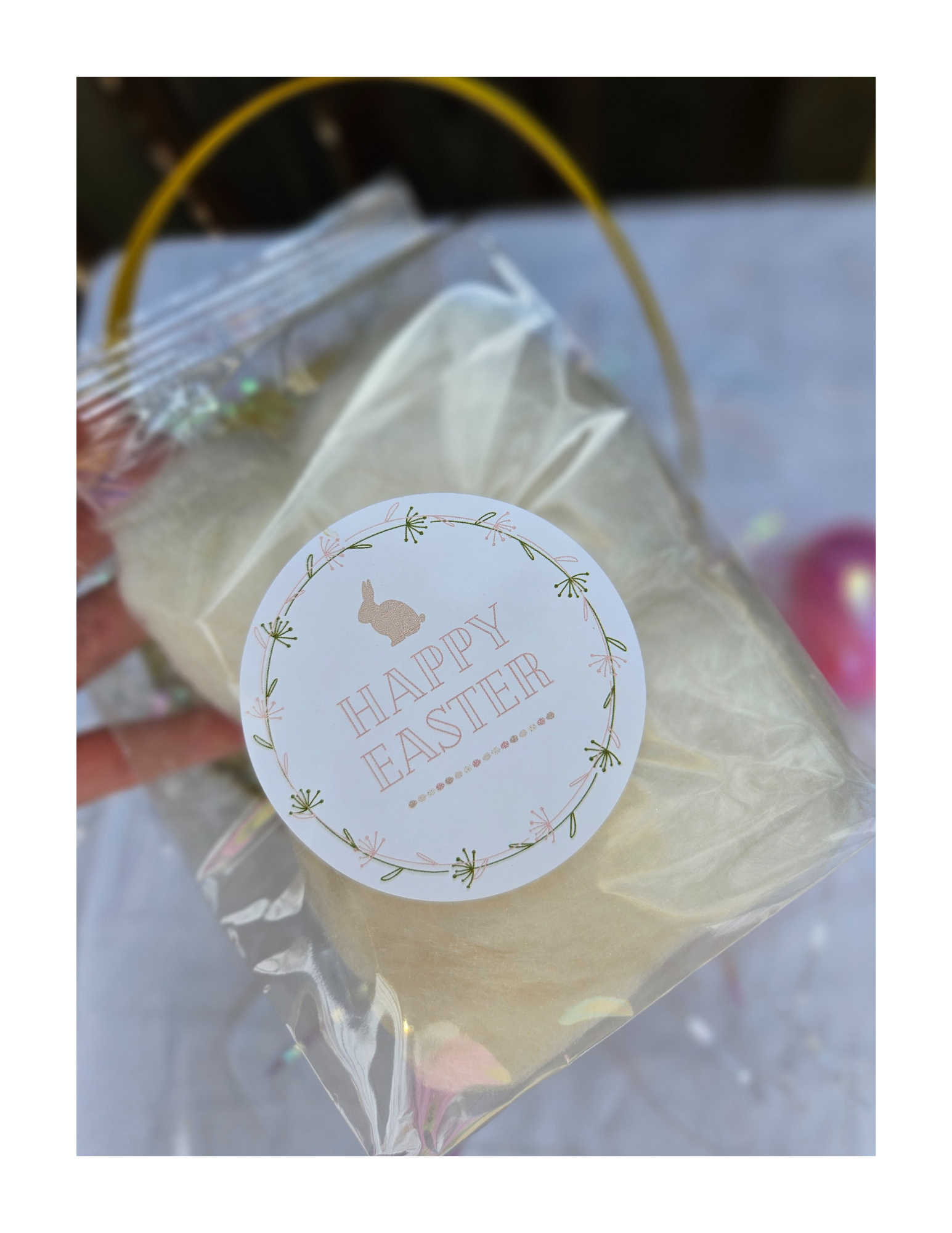 A festive clear gusseted dye-free, cotton candy bag with a round sticker that reads 'Happy Easter' and features a bunny silhouette surrounded by floral decorations.