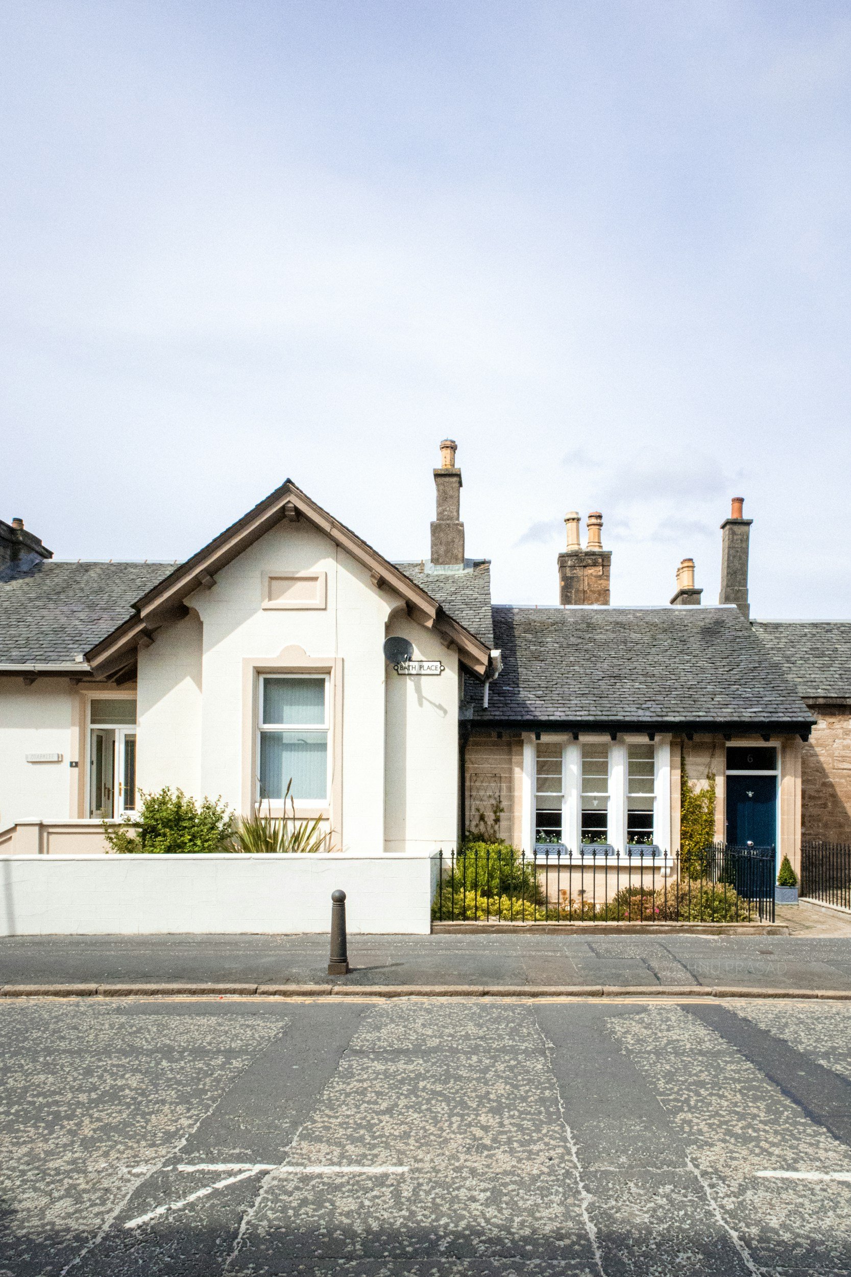 Residential houses with chimney stacks on a cloudy day, view from the street with an empty parking lot in the foreground.