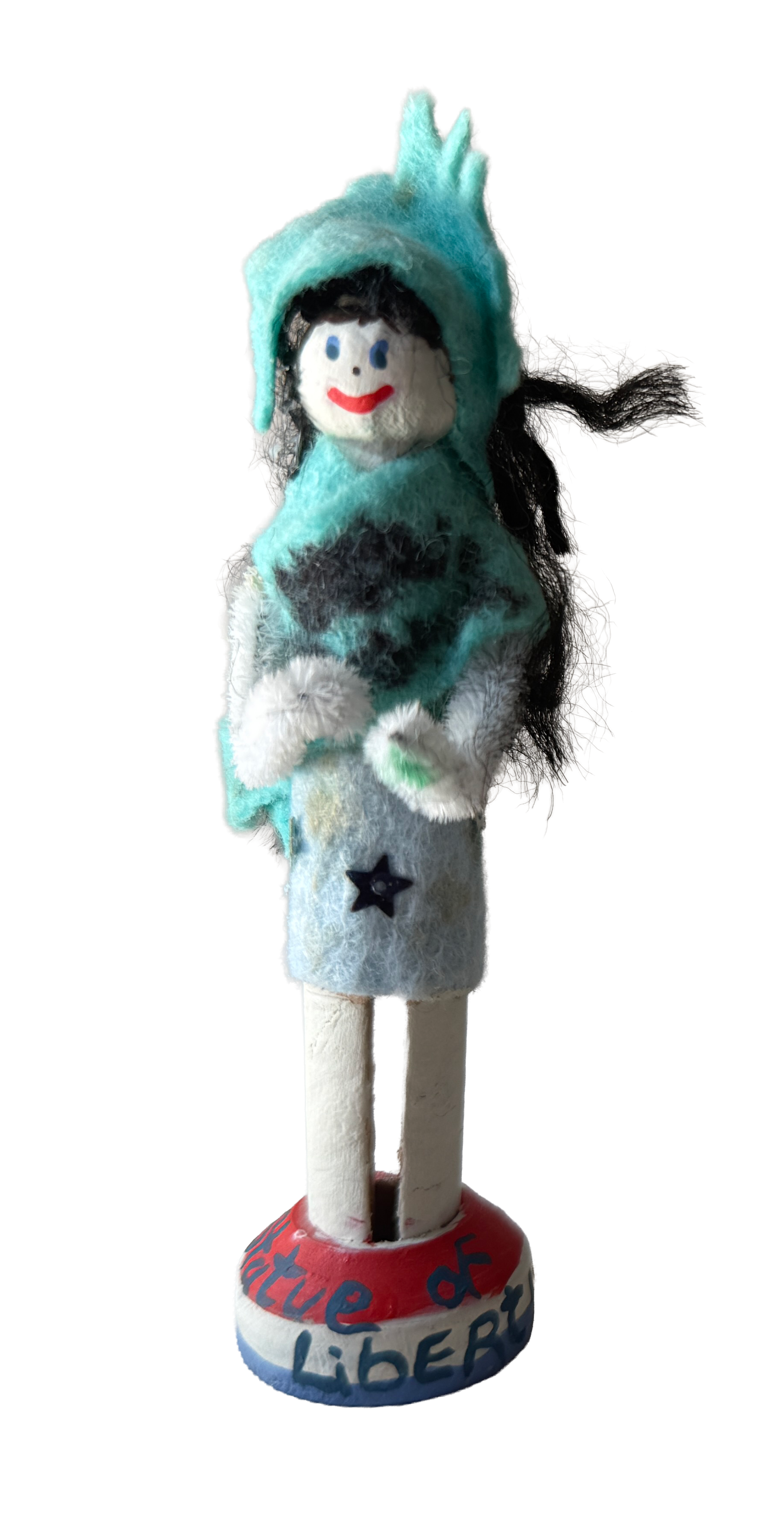 Felt puppet resembling a woman with a white face, blue eyes, and red lips, wearing a light blue hood, a black and teal patterned top, and a white skirt with a black star, standing on a red and white base with the words "The d Liberty" written on it.