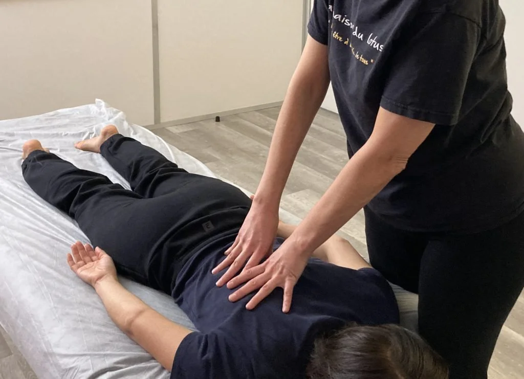 Une personne reçoit une massage sur une table de massage dans une pièce neutre.