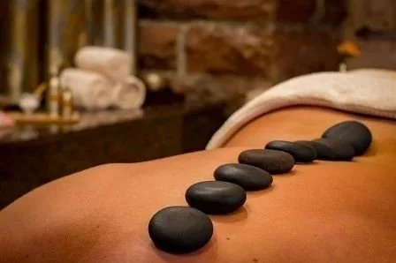 Une personne recevant un massage avec des pierres chaudes alignées sur le dos.