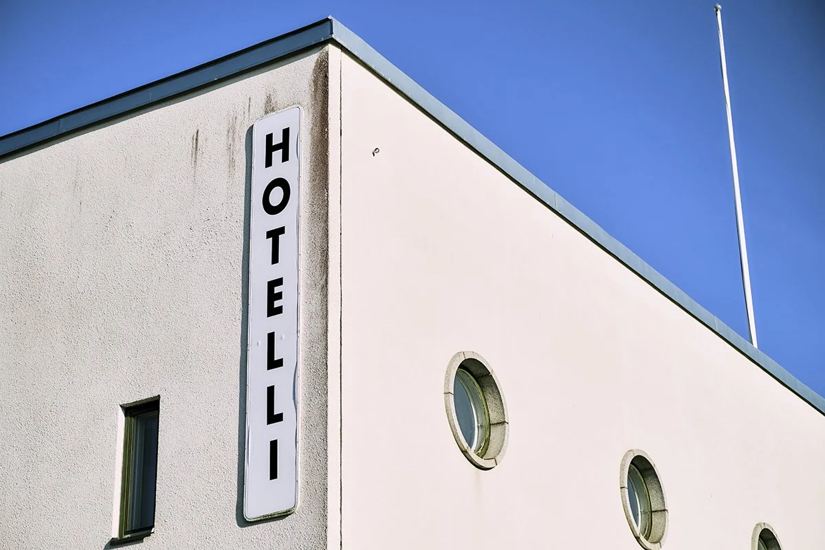 Hotellin nimikyltti kiinteistön seinässä ja kaksi pyöreää ikkunaa. Valokuvia Raumalta.