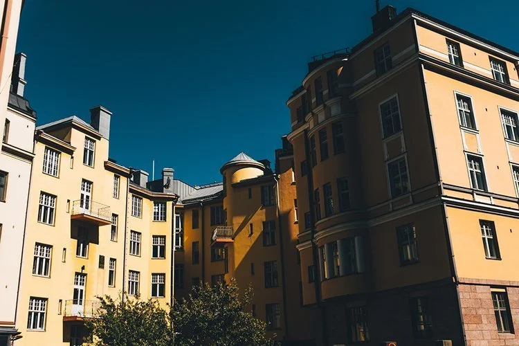 View of yellow residential buildings with multiple windows and balconies under a clear blue sky.