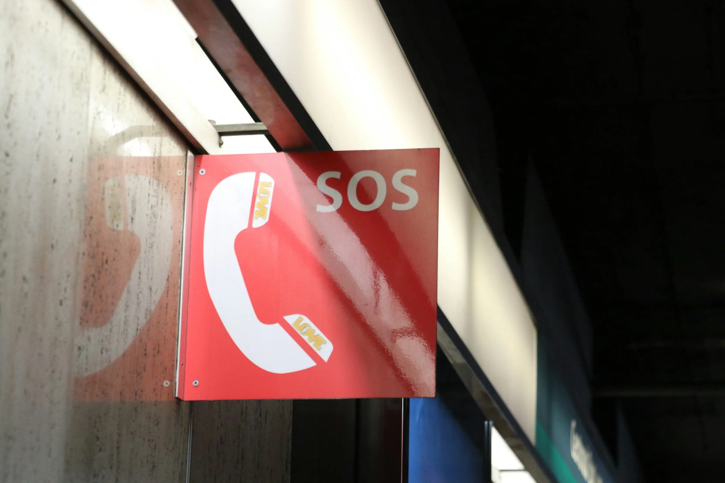 Red SOS emergency phone sign on a wooden surface.