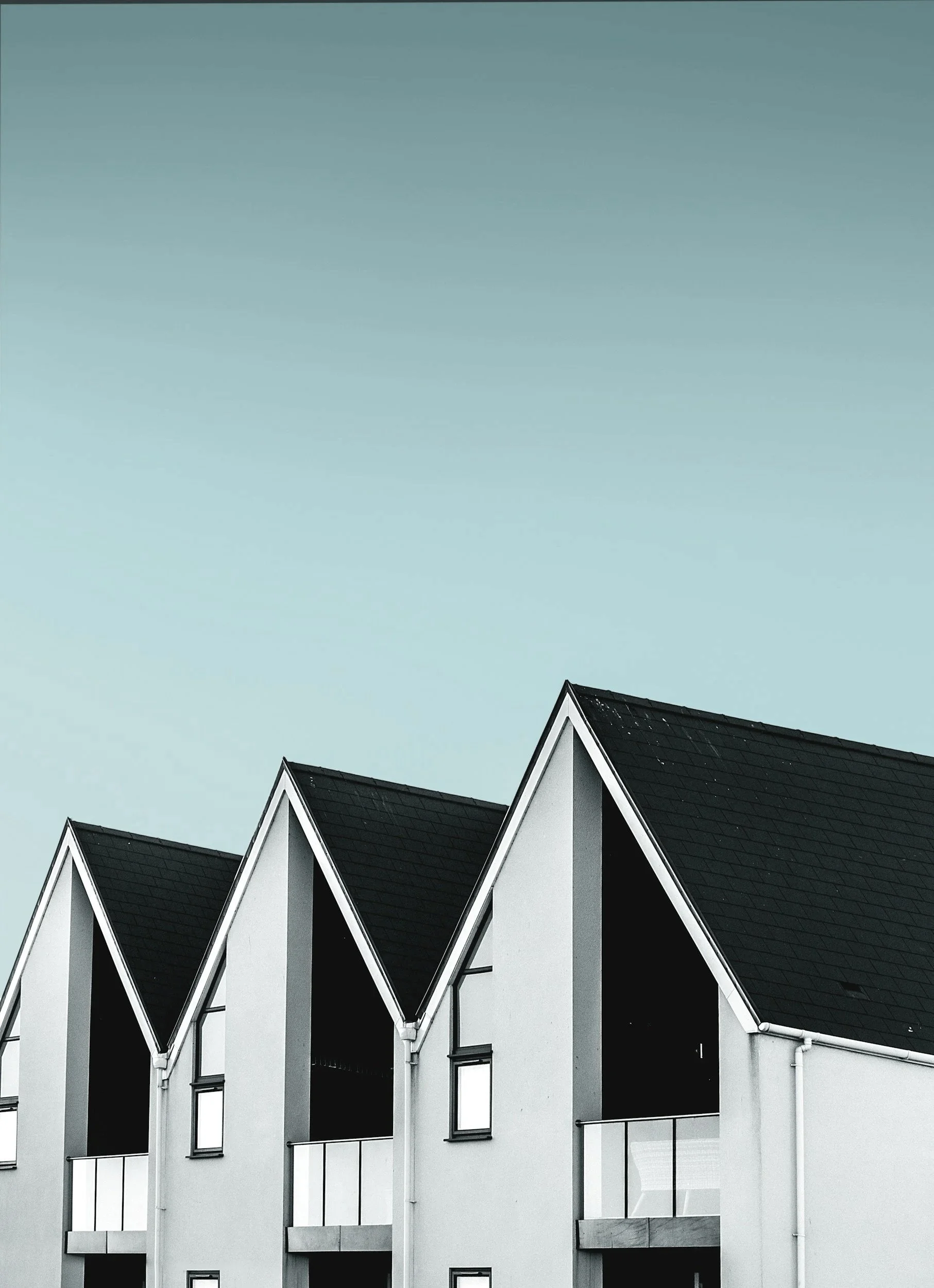 Black and white modern residential building with peaked roofs and large windows.