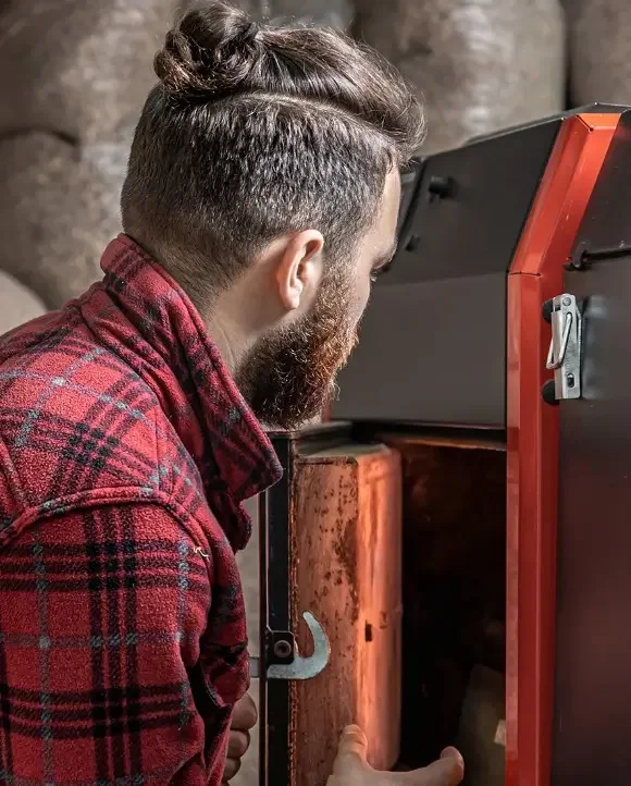plombier qui examine une chaudière en vu de son remplacement