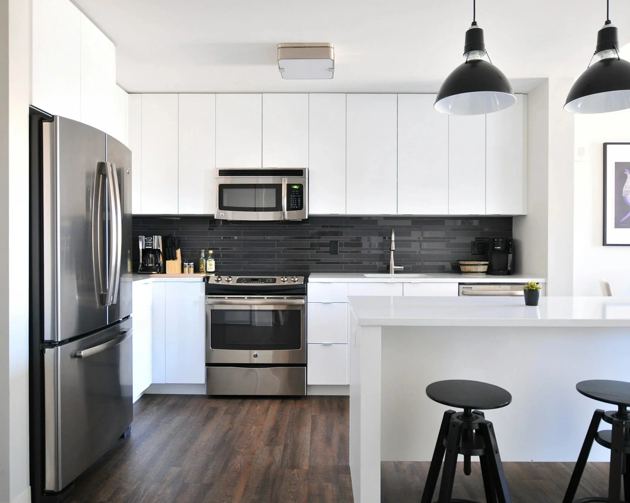 belle cuisisne rénovée avec parquet au sol, peintures blanches , meuble blanc et electroménager inox