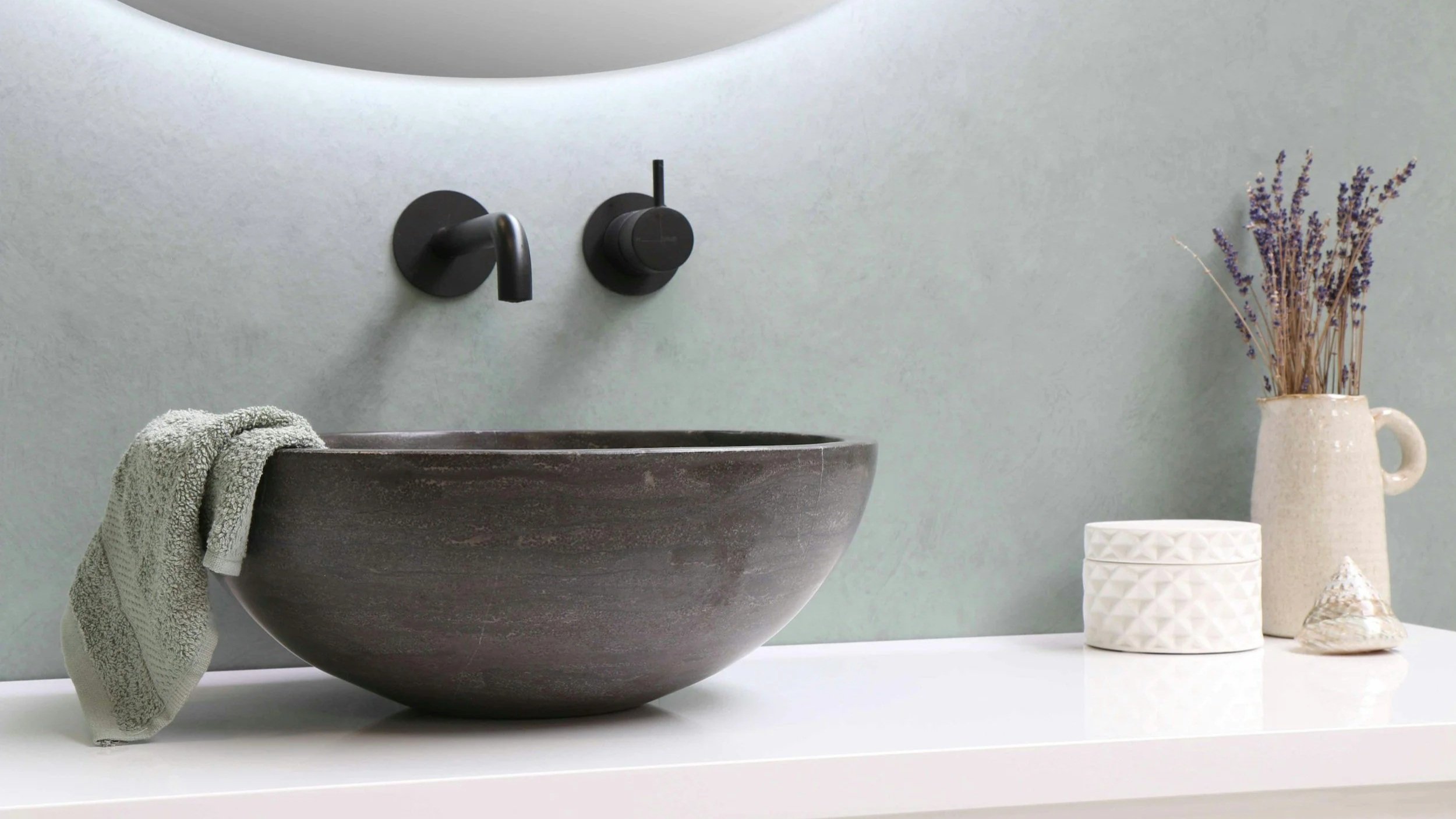 Aménagement de salle de bain contemporaine avec vasque à poser, robinetterie murale et miroir rétroéclairé.