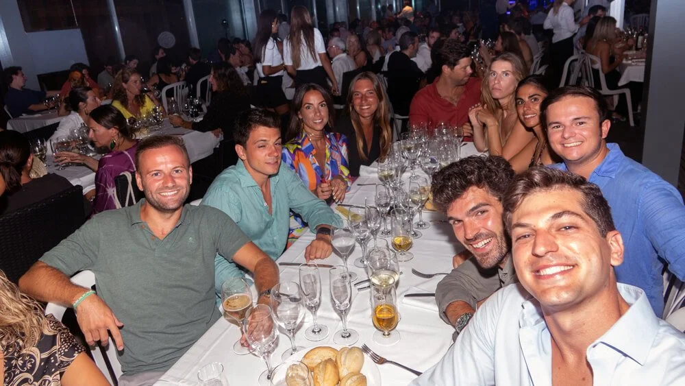 Grupo de personas sonriendo y brindando en una fiesta o comida en un restaurante elegante.