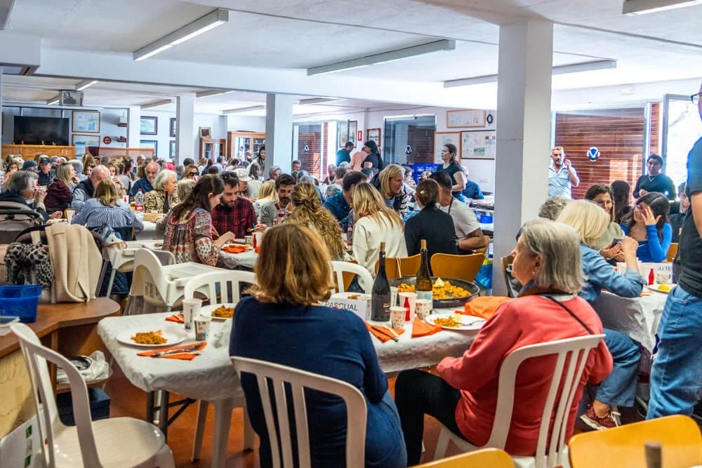 Una multitud de personas sentadas en mesas disfrutando de una comida en un salón comedor.