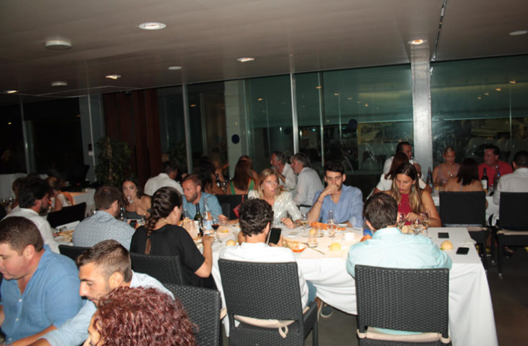 Gente cenando en un restaurante moderno con vista a través de ventanales.