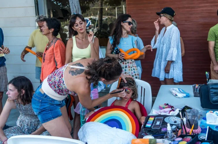 Personas en una fiesta infantil, niños y adultos, decoraciones y maquillaje para niños, mesa con accesorios y maquillaje.