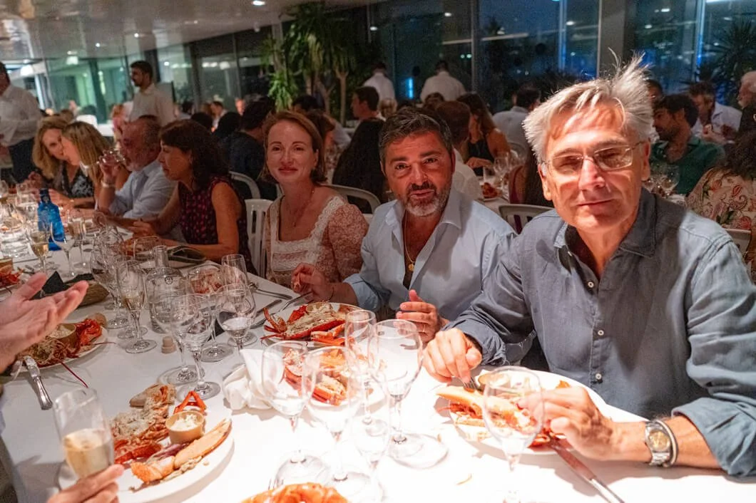 Personas en una cena elegante en un restaurante, con comida de mariscos en la mesa.