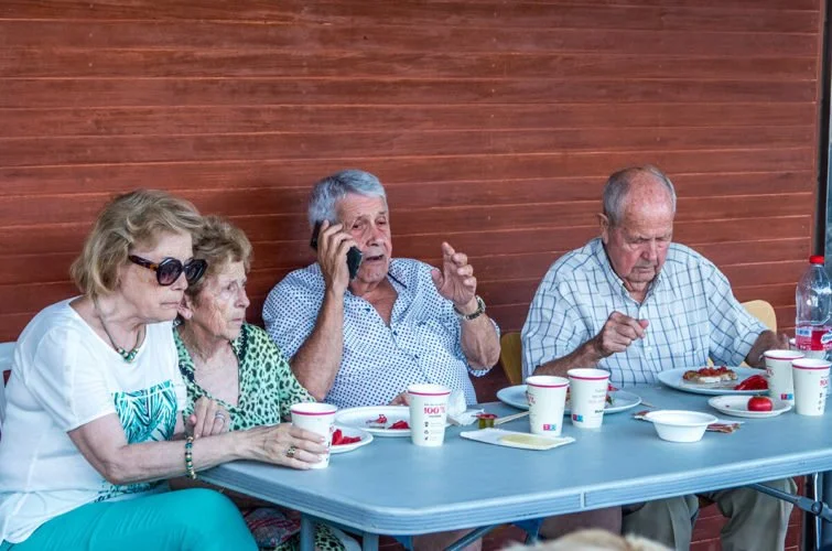 Cinco personas sentadas en una mesa brinde una reunión con comida y bebidas.