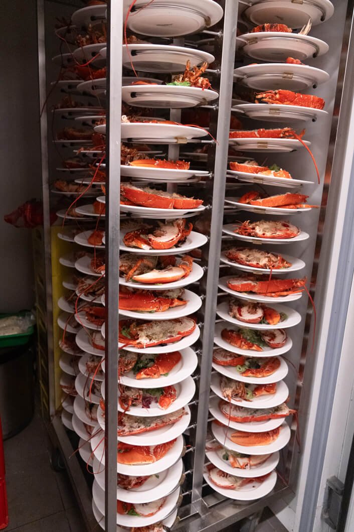 Platos con langosta en un estante metálico.