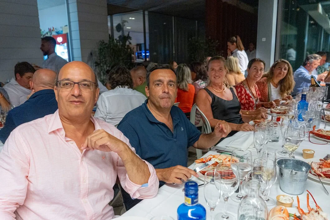Grupo de personas sentadas en una mesa en un restaurante, celebrando con comida y bebidas.