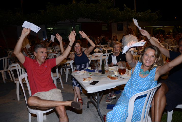 Grupo de personas jubiladas celebrando en una reunión al aire libre, levantando las manos y sonriendo.
