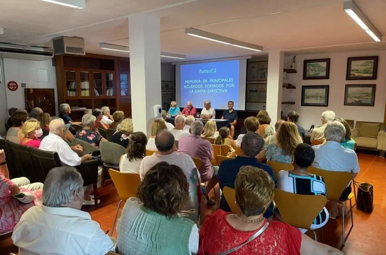 Reunión de varias personas en una sala, frente a una proyección que muestra la diapositiva titulada 'Punto 2.2. Memoria de principales acuerdos tomados por la Junta Directiva'.