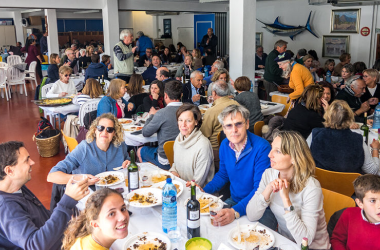 Personas disfrutando de una comida en un restaurante concurrido con decoraciones de mar y pescado en la pared.