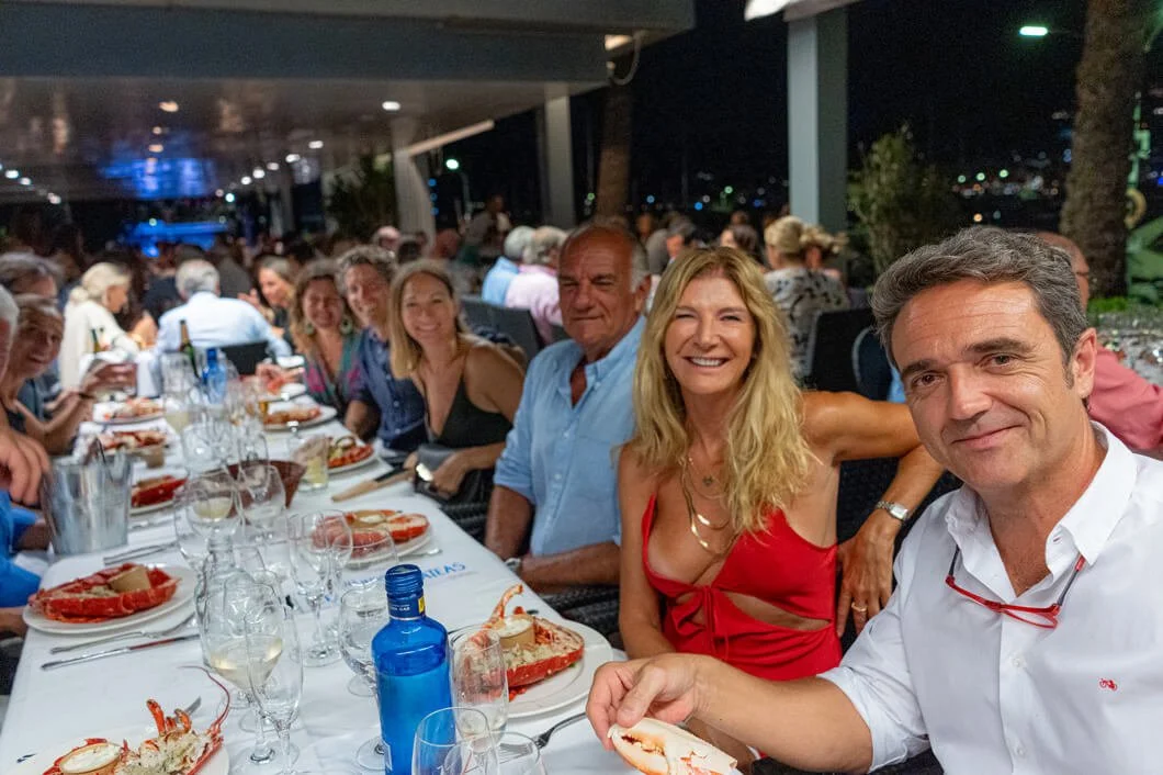 Grupo de personas en una cena o comida en un restaurante, disfrutando y sonriendo, en un ambiente de noche con decoração elegante.