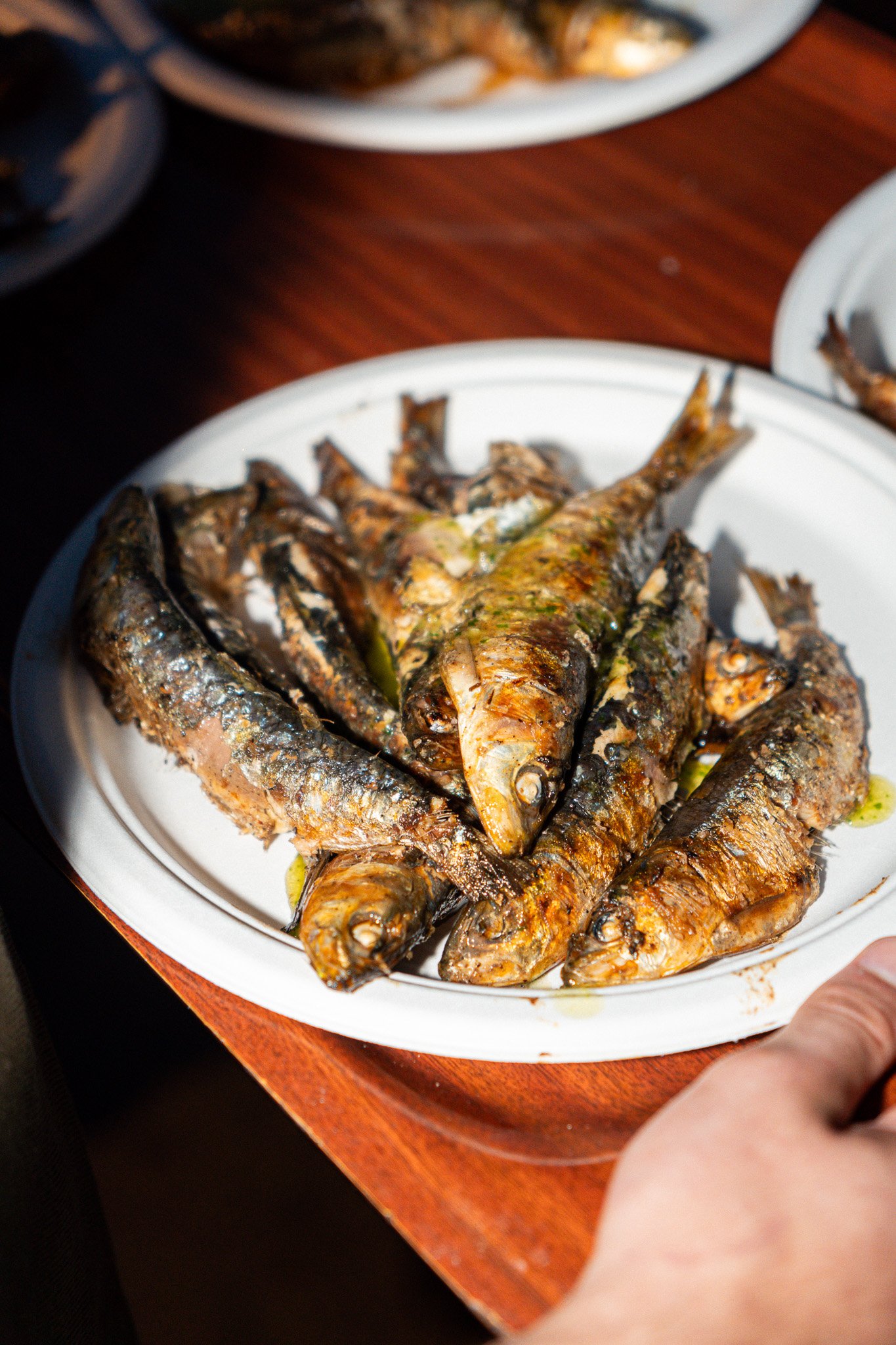 Plato con varios pescados asados en una bandeja blanca, en un ambiente que parece un restaurante