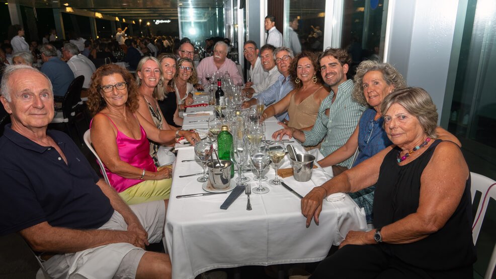 Grupo de personas sentadas en una mesa larga en un restaurante, celebrando una reunión o evento social.